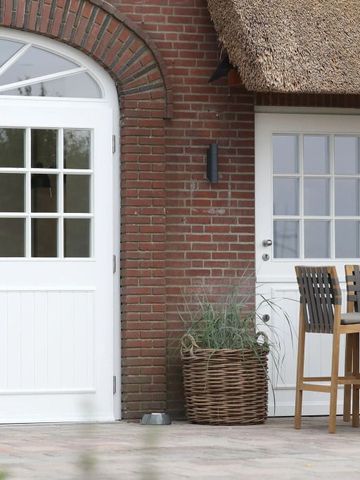 Hotelterrasse mit Backsteinfassade und traditionellen reetgedeckten Türen