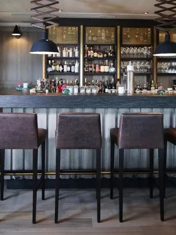 Elegante Bar mit stilvollen Lederhockern und gut bestücktem Regal