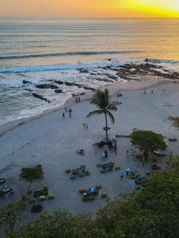 Sonnenuntergang am Strand mit Palmen und sanften Wellen.