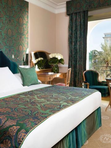 Luxuriös eingerichtetes Hotelzimmer mit grüner und goldener Dekoration und Balkon