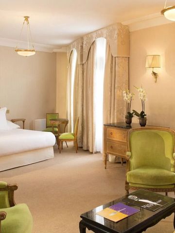 Großes Hotelzimmer mit grünen Sesseln und natürlichem Licht