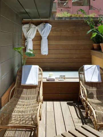 Private Terrasse mit Liegestühlen und Badewanne, umgeben von grünen Pflanzen.