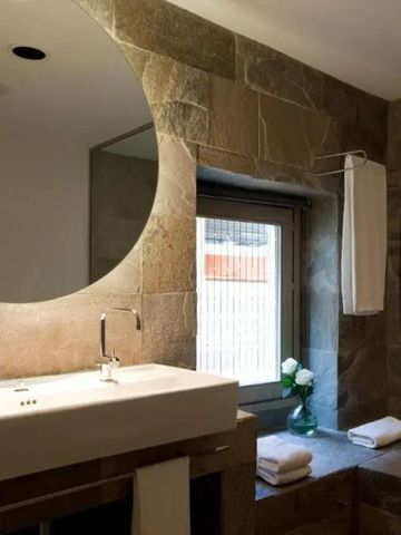 Luxuriöses Badezimmer mit großem Spiegel und eleganten Armaturen.