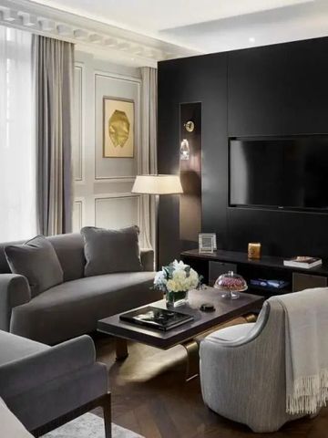 Moderner Wohnbereich im Hotelzimmer mit grauem Sofa und großem Fernseher