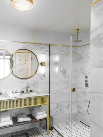 Modernes Badezimmer mit Marmorfliesen und goldenen Akzenten.
