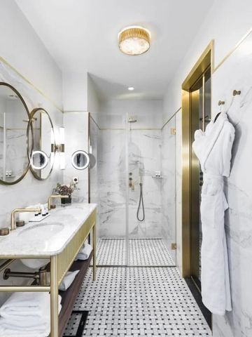 Geräumiges Badezimmer mit Regendusche und goldenen Details.