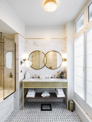 Helles Badezimmer mit großen Spiegeln und goldenen Elementen.