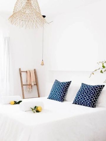 Schlafzimmer mit weißen Wänden und blauen Kissen auf dem Bett