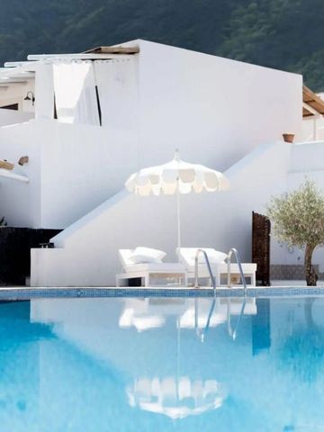 Poolbereich mit weißen Gebäuden und einem Sonnenschirm im Hintergrund