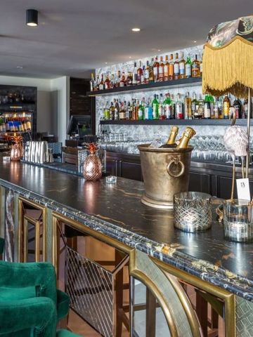 Bar mit goldenen Elementen und erlesenen Spirituosen in stilvollem Ambiente.