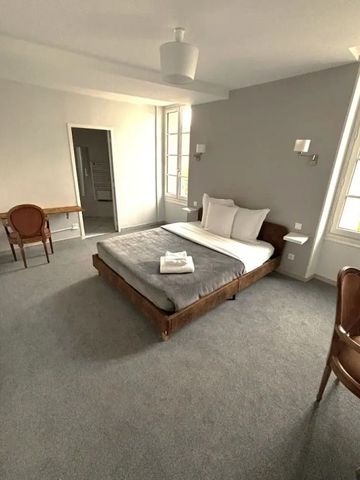 Helles Zimmer mit Doppelbett, Schreibtisch und großen Fenstern.