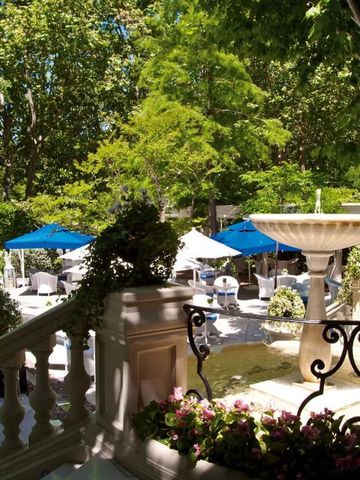 Charmanter Hotelgarten mit Brunnen und Sonnenschirmen