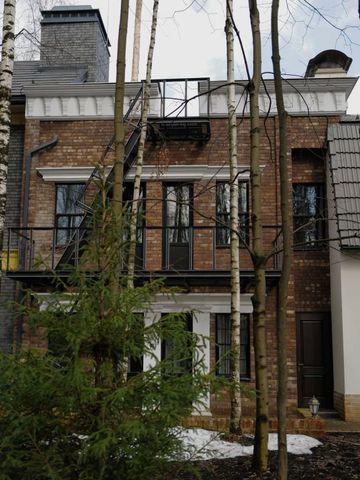 Backsteinfassade mit Feuerleiter und weißen Säulenakzenten hinter Bäumen.