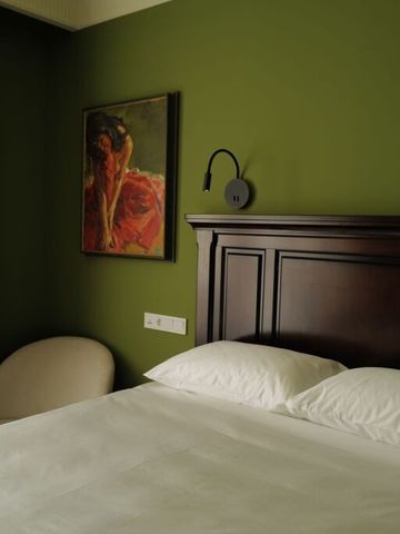 Elegantes Schlafzimmer mit grünen Wänden und hochwertigem Holzbettrahmen