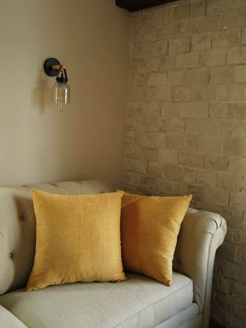 Gemütlicher Sessel mit gelben Kissen und Wandlampe in elegantem Raum