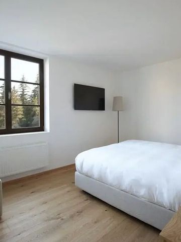 Helles Schlafzimmer mit Holzboden und großem Fenster, das Bäume zeigt
