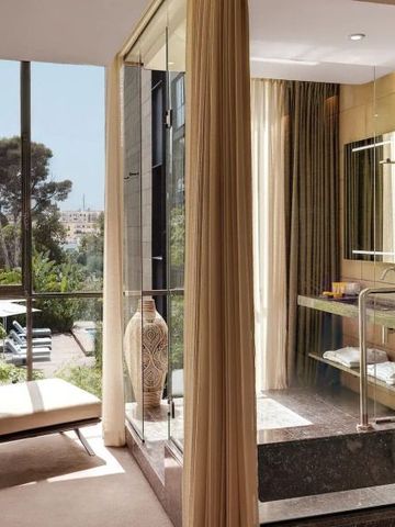 Hotelbad mit großen Fenstern und Blick auf einen Garten