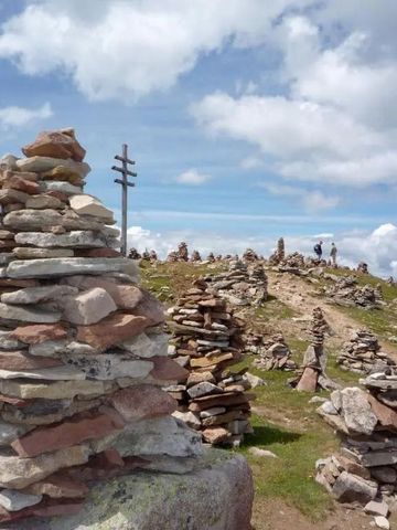 Steinmännchen auf einem Bergpfad unter blauem Himmel