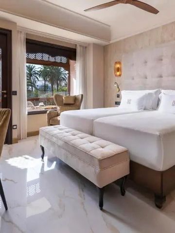 Hotelzimmer mit zwei Betten und Blick auf Palmen.