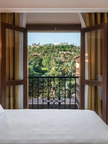 Hotelzimmer mit Blick auf grüne Landschaft durch geöffnete Balkontüren