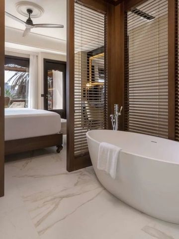 Elegantes Badezimmer mit freistehender Badewanne und Blick ins Schlafzimmer