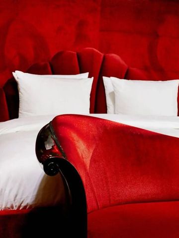 Exquisit eingerichtetes Schlafzimmer mit rotem Samt und weißen Kissen