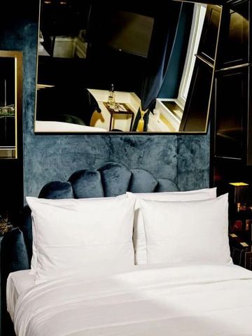 Elegantes Hotelzimmer mit luxuriösem Doppelbett und dunkler Wandverkleidung