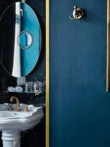 Schickes Badezimmer mit rundem Spiegel und goldenen Armaturen