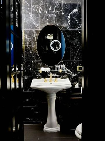 Badezimmer mit schwarzer Marmorwand und ovalem Spiegel