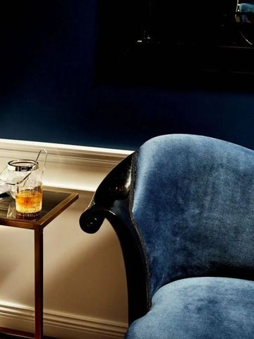 Gemütliche Sitzecke mit dunkelblauem Sessel und Getränk auf Beistelltisch