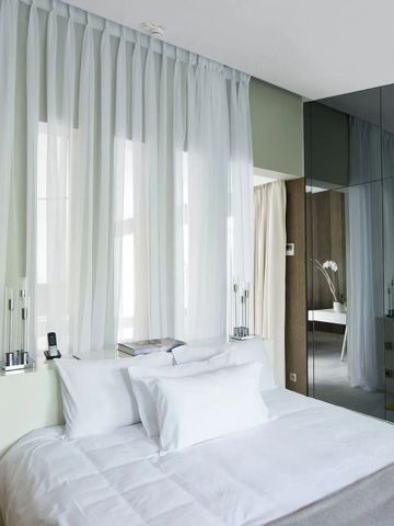 Hotelzimmer mit lichtdurchfluteten Vorhängen und Spiegelwand