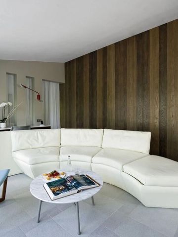 Moderner Wohnbereich mit weißem Ledersofa und Holzwand