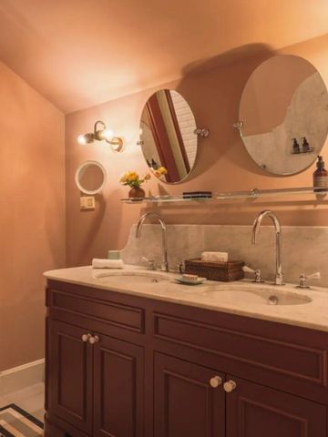 Luxuriöses Badezimmer mit zwei runden Spiegeln und Marmorwaschtisch