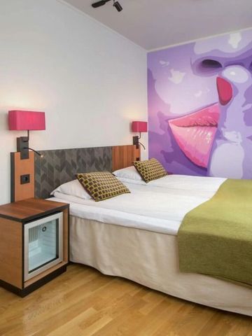 Modernes Hotelzimmer mit kreativem Wandgemälde in Lila und Rosa.