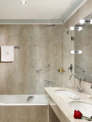 Marmorbadezimmer mit Badewanne und dekorativer Beleuchtung.