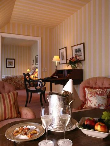 Gemütliches Wohnzimmer mit Sesseln, Tisch und Champagnereimer in warmen Farben