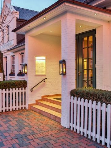 Eingangsbereich des Hotels mit weißer Fassade und Zäunen im Abendlicht