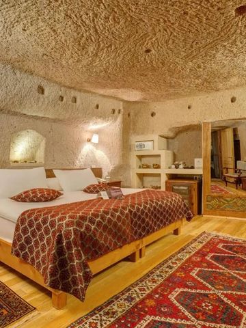 Komfortables Höhlenzimmer mit traditionellem Teppich und Natursteinwänden.