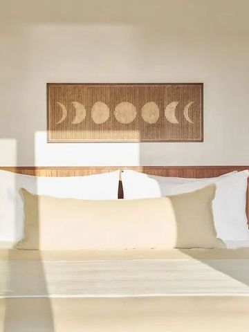 Helles Schlafzimmer mit Kunst an der Wand und großen Kissen auf dem Bett