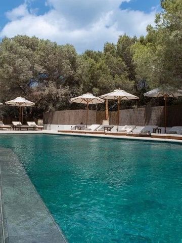 Großer Pool unter Sonnenschirmen inmitten grüner Umgebung.