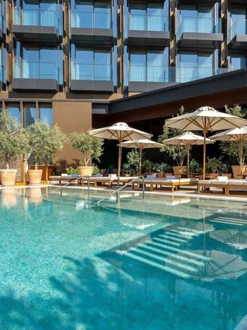 Pool mit Liegen und Sonnenschirmen vor einer modernen Hotelfassade in Dubai