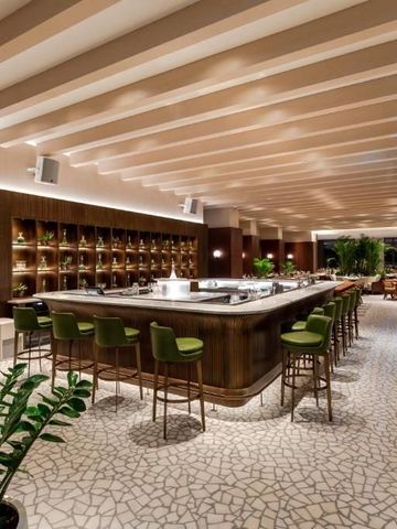 Elegante Bar mit modernen grünen Hockern und hellen Innendetails