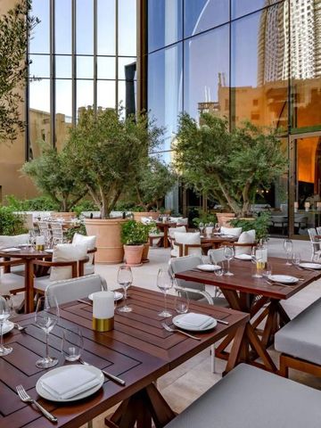 Gepflegter Außenbereich mit Holztischen und üppiger Bepflanzung vor moderner Fassade