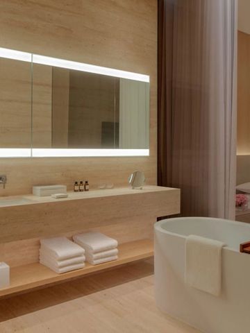 Moderner Badezimmerbereich mit freistehender Wanne und großem Spiegel