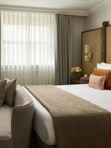 Helles Hotelzimmer mit großen Fenstern und gemütlichem Bett