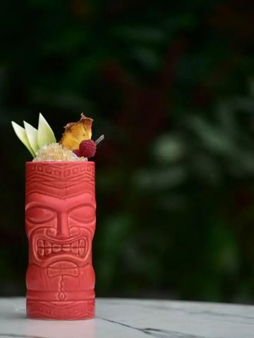 Exotischer Cocktail in einem einzigartigen Tiki-Becher mit Früchtegarnitur