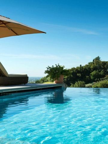 Infinity-Pool mit Liegen und Sonnenschirm vor einer grünen Landschaft