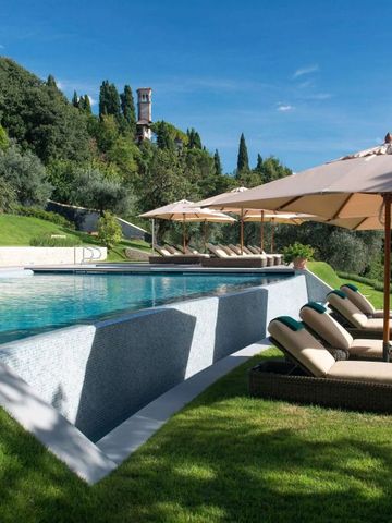 Großer Swimmingpool mit Sonnenliegen und grünem Hügel im Hintergrund