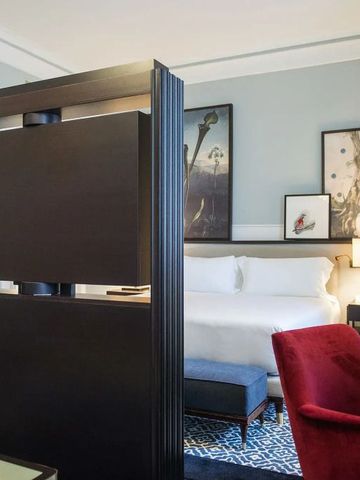 Geräumiges Hotelzimmer mit einem modernen Raumteiler und roten Akzenten