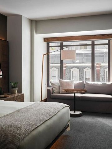 Geräumiges Schlafzimmer mit bequemer Sitzgelegenheit und natürlichem Licht.